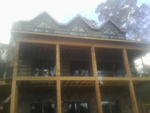 Dormers and porch framing on a large log home under construction — Roof Coating work by our crew in Stovall