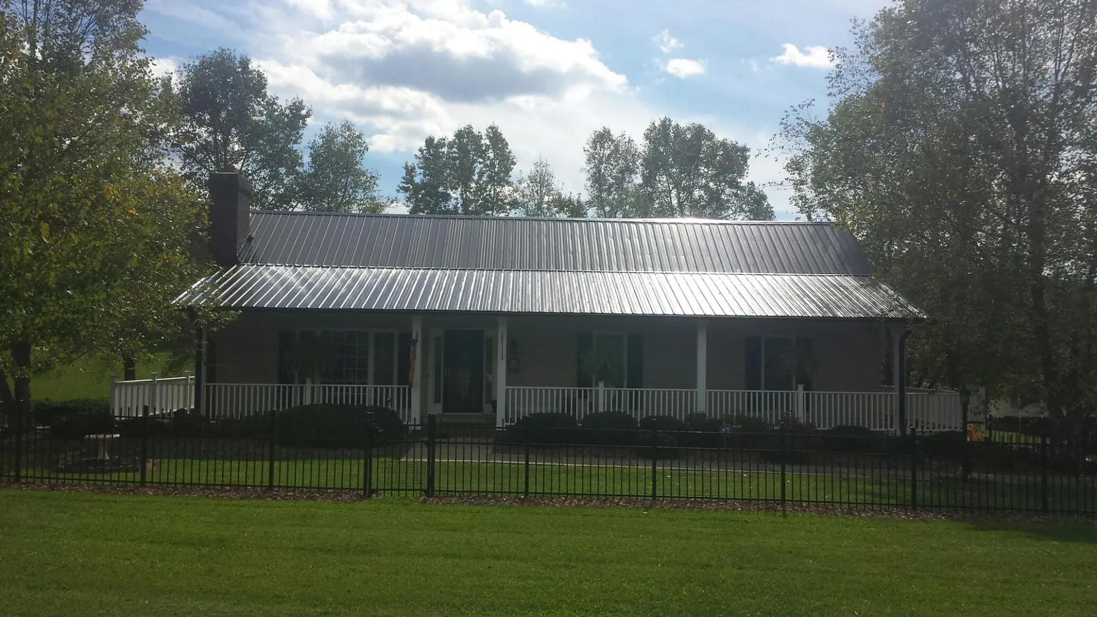 Gray metal roof on a brick ranch with a full width front porch — Gutter Guard Installation work by our crew in Stovall