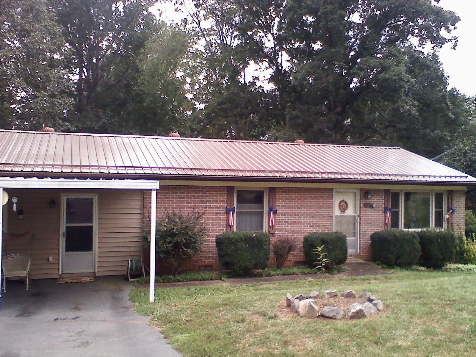 Bronze metal roof and carport on a brick ranch home — Roof Repair work by our crew in Stovall